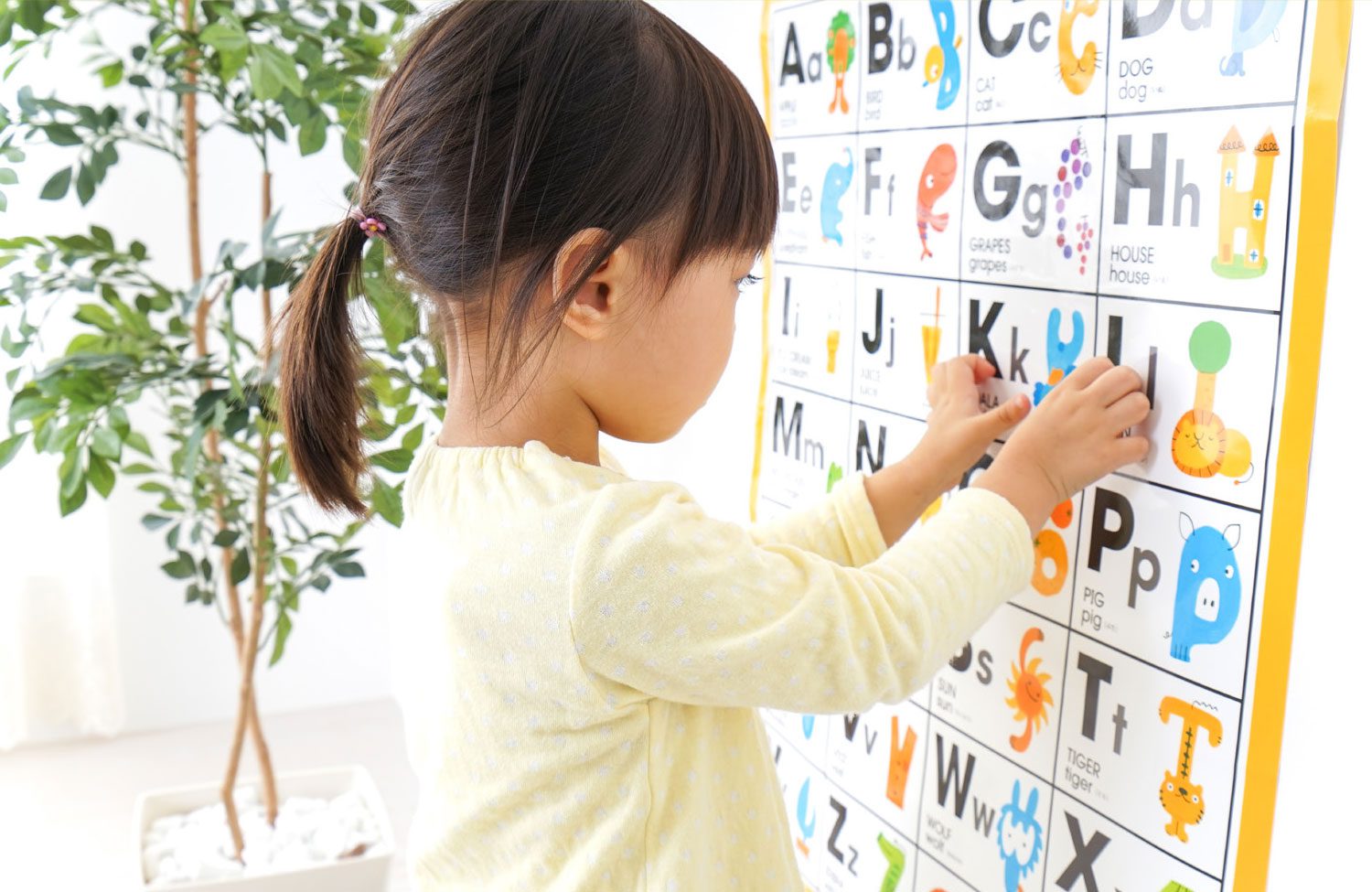 child works with letters on a decorated wall