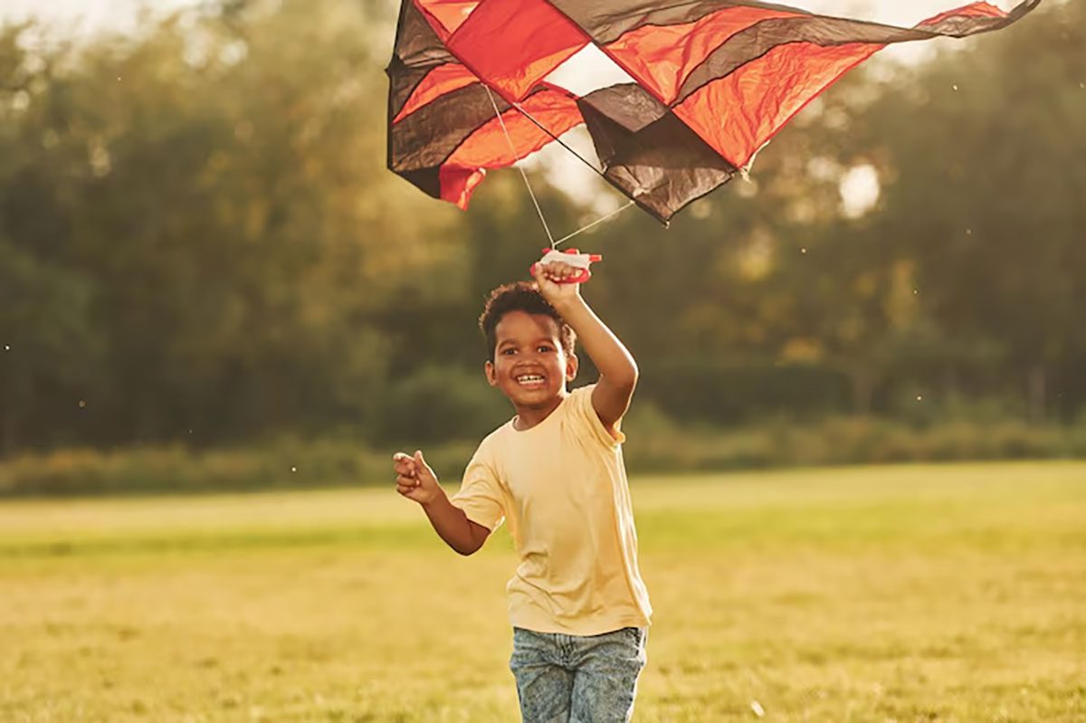 child running through field with kite