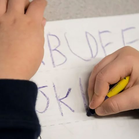 child writing with crayons