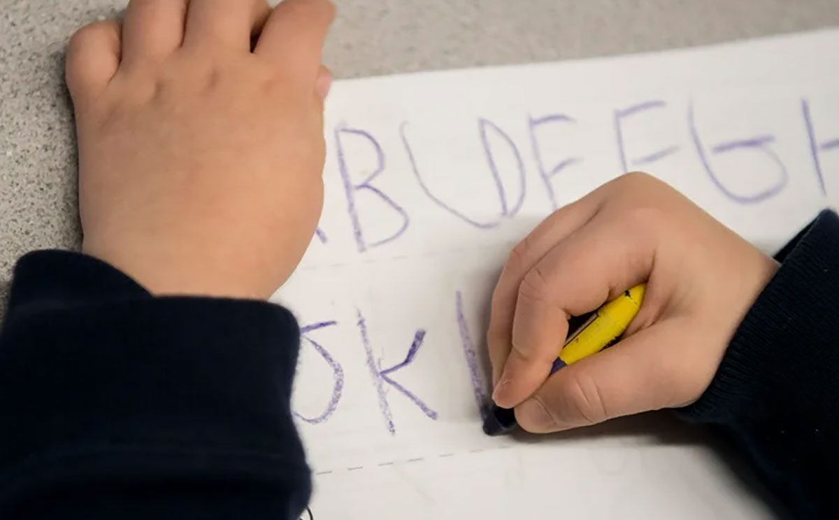 child writing with crayons